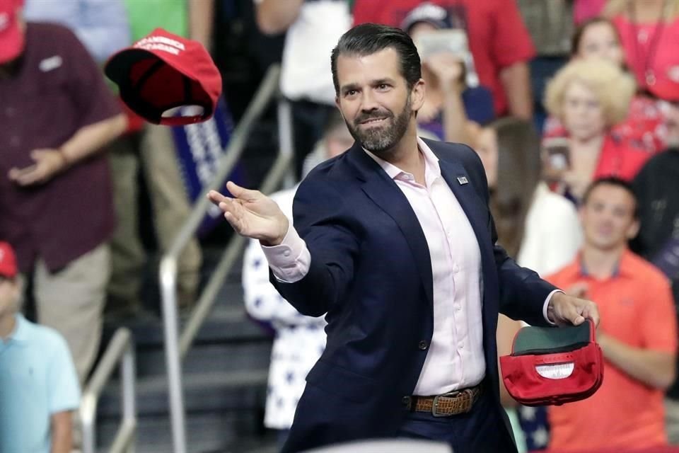 Donald Trump Jr. arroja gorras con la leyenda 'Make America Great Again' durante el mitin.