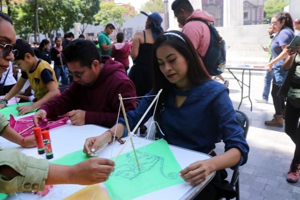 A un costado del Hemiciclo a Juárez, decenas de personas interrumpen el paseo dominical y se detienen en mesas dispuestas con materiales para confeccionar el centenar de papalotes.