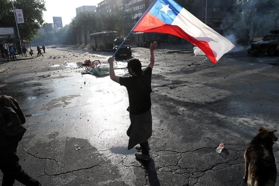 A demonstrator holds a Chilean flag during a protest against the increase in subway ticket prices in Santiago, Chile, October 19, 2019. REUTERS/Ivan Alvarado