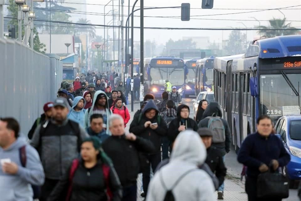 Personas caminan en busca de transporte fuera de la estación de metro La Cisterna que se encuentra cerrada este lunes en Santiago.