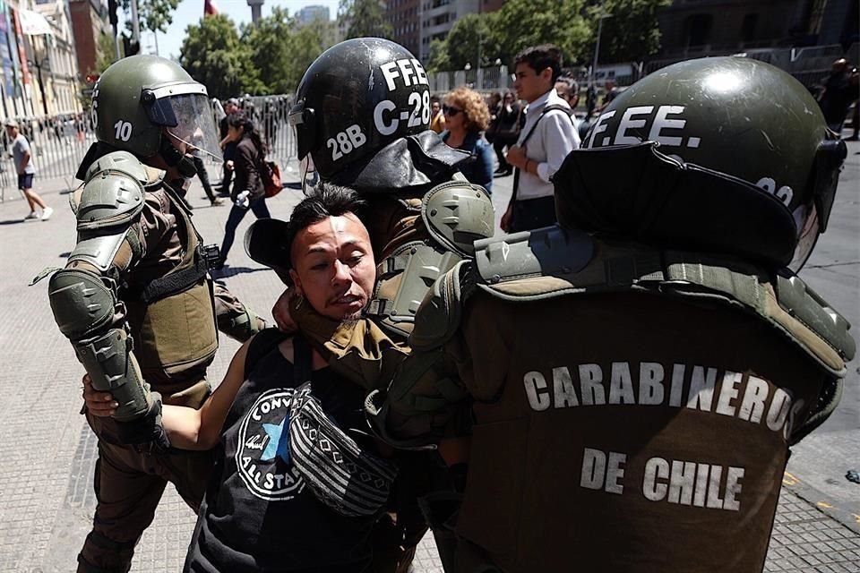 Carabineros detienen a un manifestante durante las movilizaciones en contra del Gobierno en todo el país.