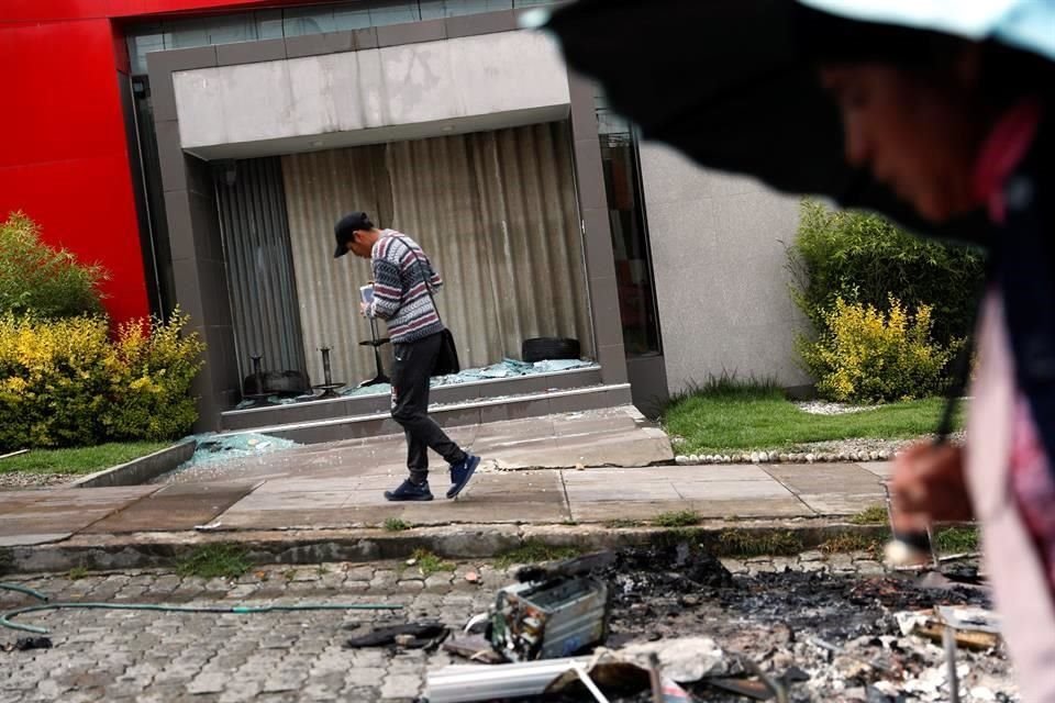 Gente pasa frente a la entrada de una tienda saqueada.