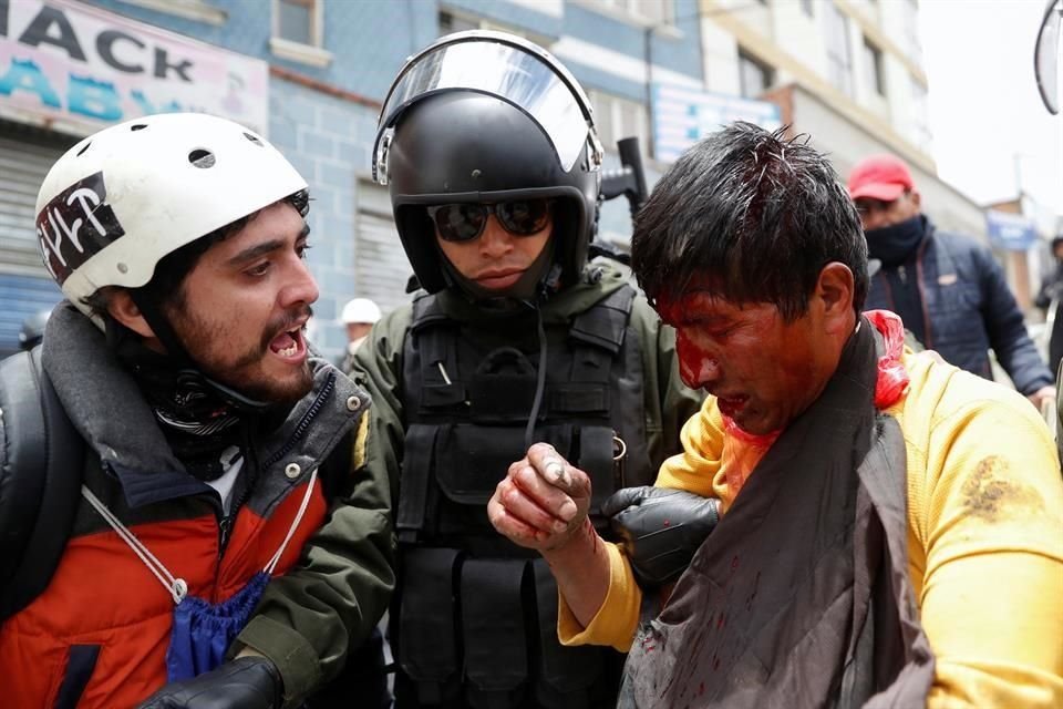 Un manifestante grita a un hombre resguardado pos las autoridades.