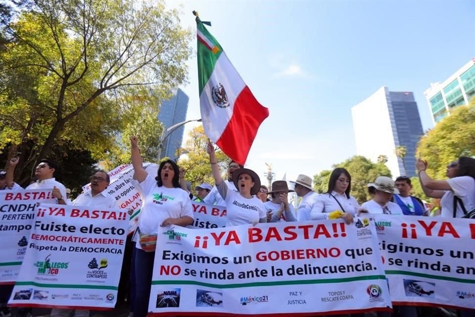 Los manifestantes visten de blanco y portan banderas de México.