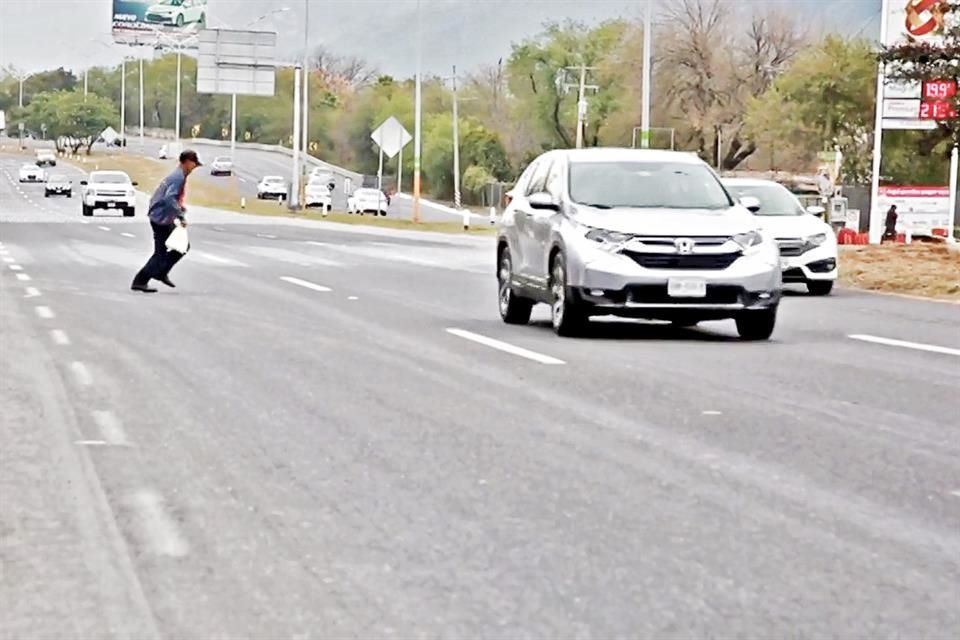 Un trabajador cruza corriendo la carretera, donde en un tramo de 21 kilómetros han muerto 16 personas en cinco años.