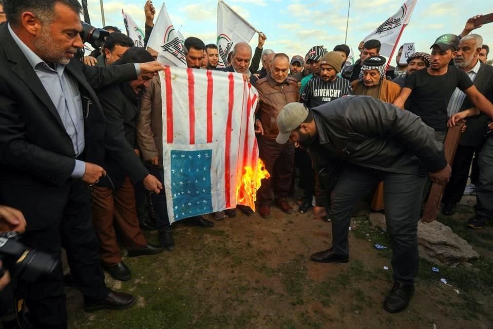 Personas en Irak queman una bandera estadounidense tras los ataques de EU a una milicia en ese país.