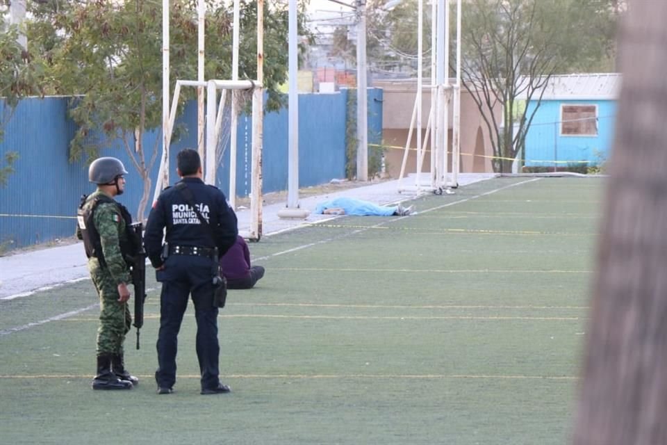 Elementos de la Guardia Nacional y de la Policía municipal custodian el cuerpo de Rubén Moreno Ortíz, de 51 años en una cancha de la Unidad Deportiva San Gilberto.