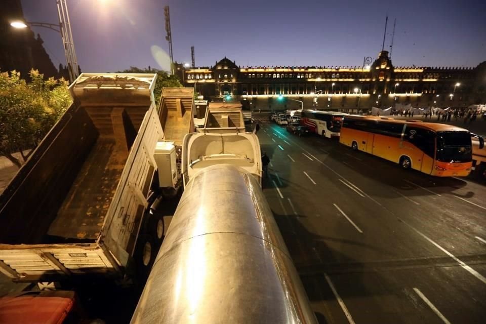 Transportistas usan camiones de carga para bloquear circuito de Zócalo capitalino para demandar a autoridades contratos de acarreo de material presuntamente para obras de Aeropuerto de Santa Lucía.