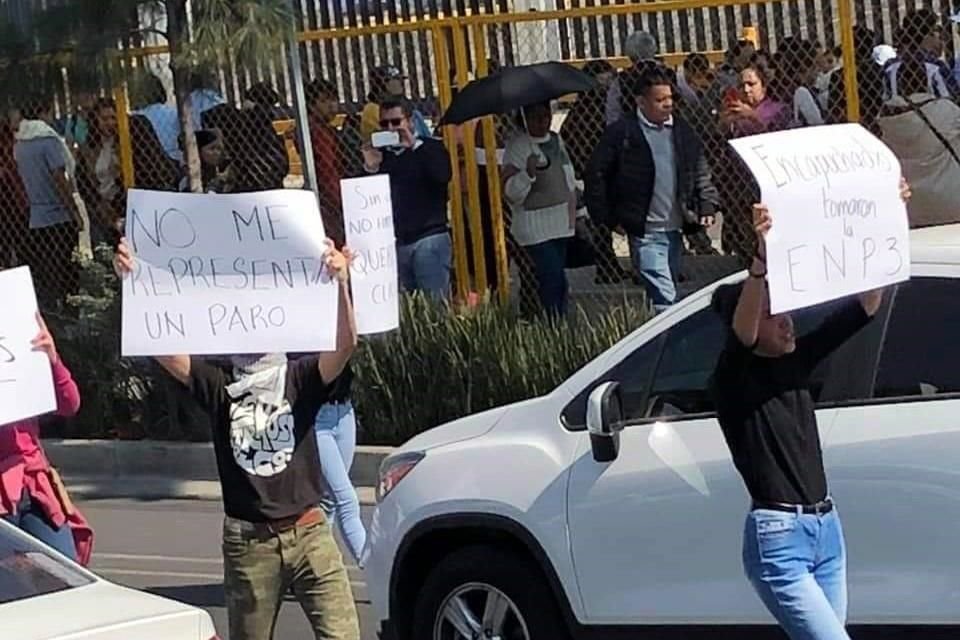 Alumnos -tanto hombres como mujeres- con credencial en mano levantan pancartas frente a Avenida Eduardo Molina.