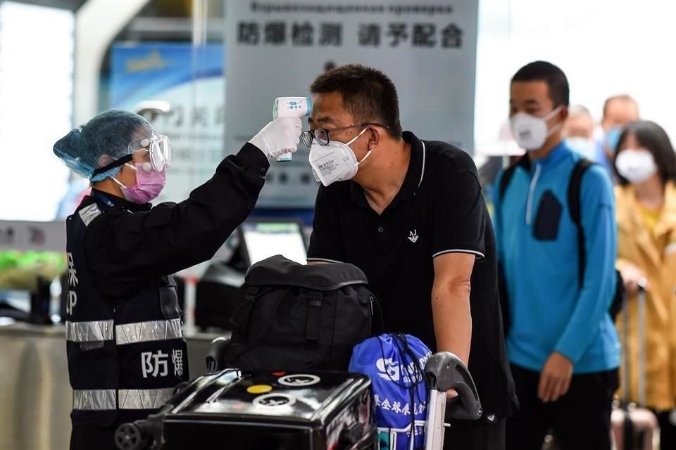 Un trabajador de seguridad verifica la temperatura de un pasajero en el Aeropuerto Internacional Phoenix de Sanya, en Hainan, al sur de China.