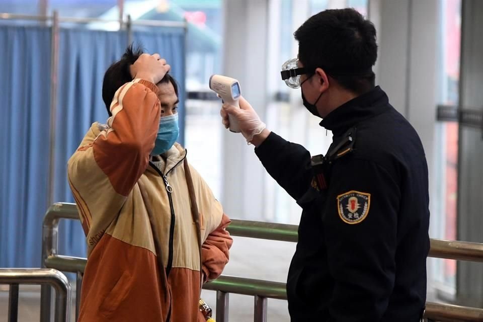 Un empleado revisa la temperatura corporal de un pasajero en la salida de la Estación de Ferrocarril Oeste de Beijing, en Beijin.