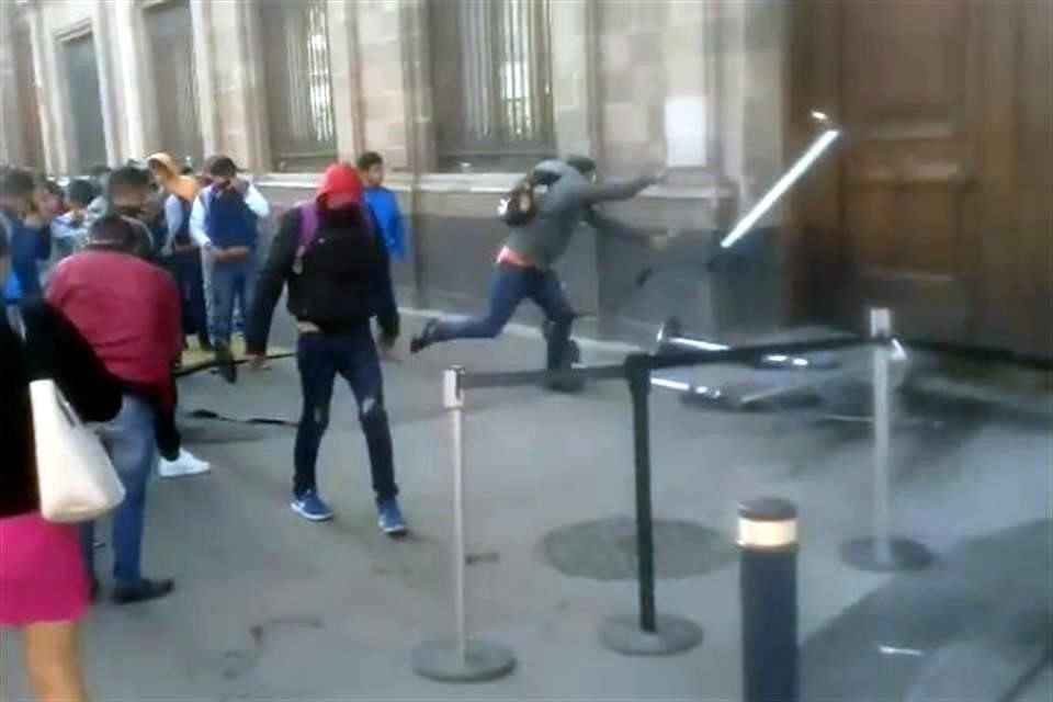 Algunos jóvenes lanzaron vallas guardarraíles contra la puerta.
