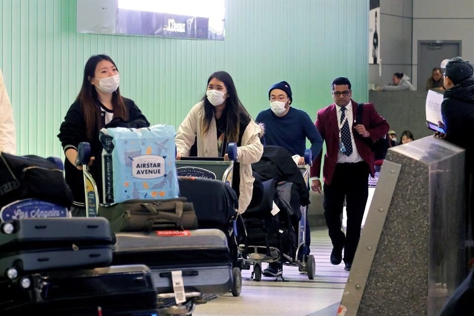 Pasajeros llegan provenientes de Shangai, China, a Los Ángeles, EU.