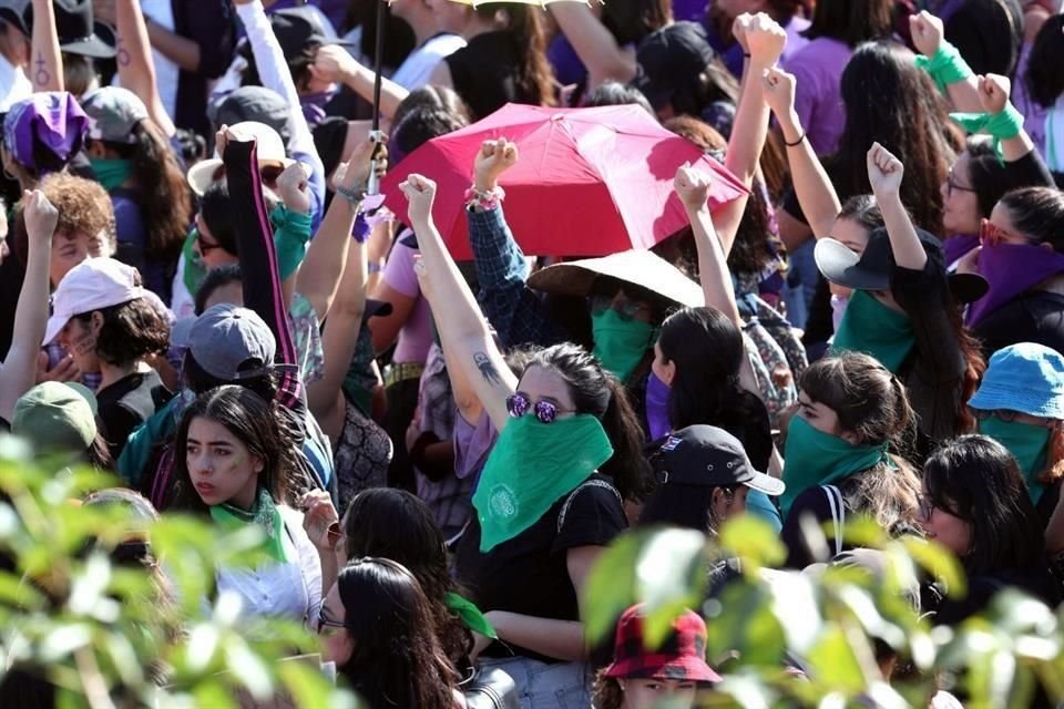 Mujeres portan pañuelos verdes y morados.