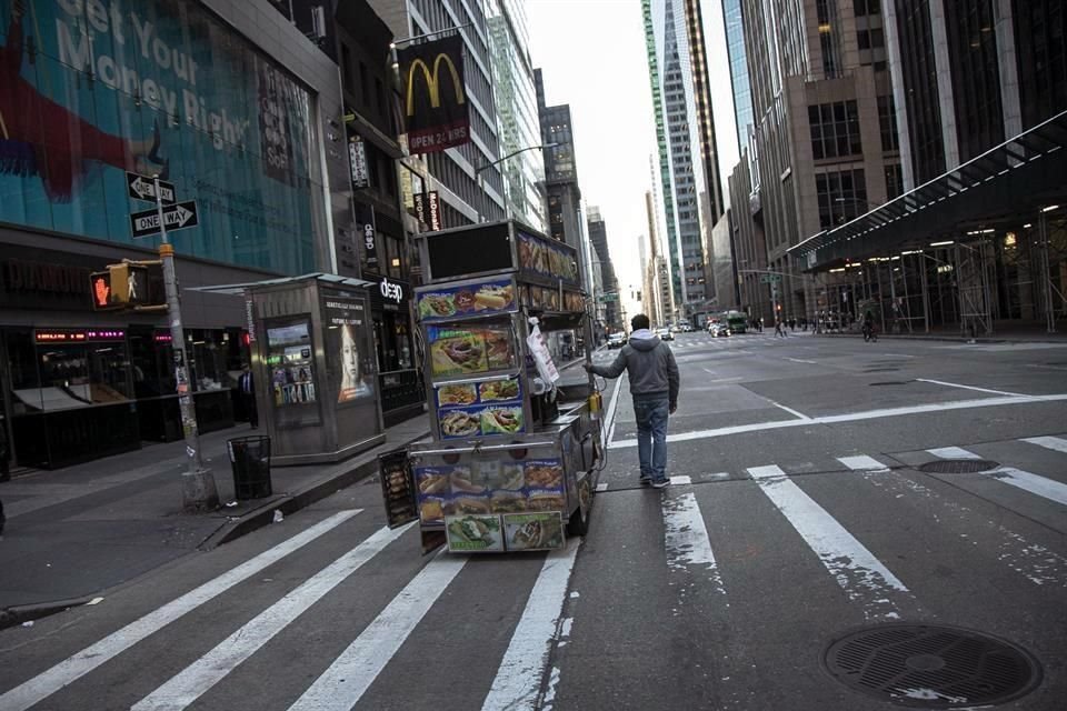 Un vendedor de comida mueve su puesto en medio de una calle semivacía en Nueva York.