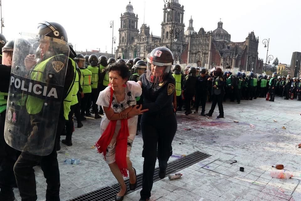 Una señora que participaba en la marcha fue ayudada a salir por una agente luego de haberse interpuesto entre policías y manifestantes que lanzaban objetos contra las uniformadas; 'traidora', le gritaban.