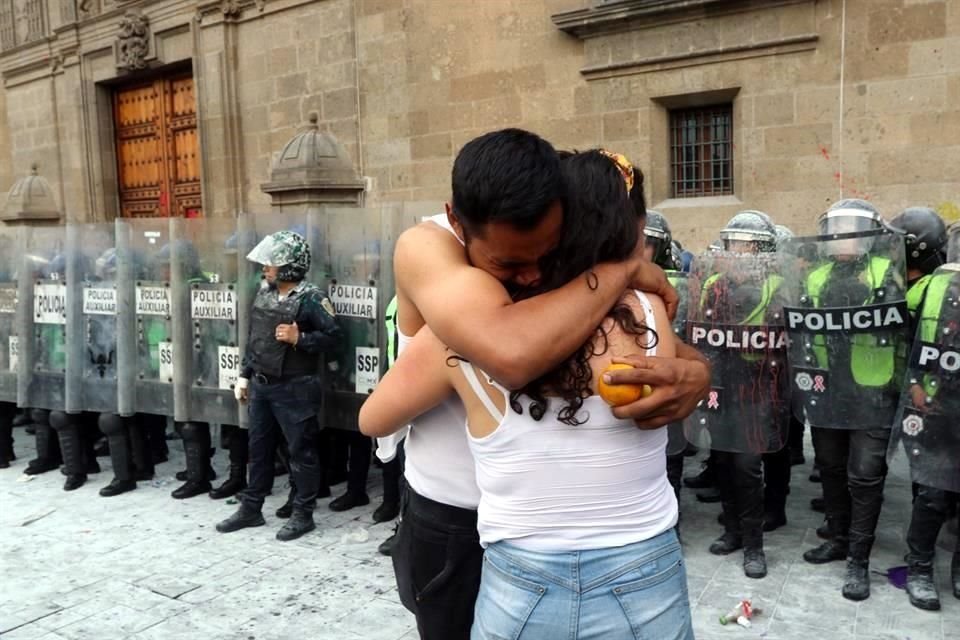 Un joven que acompañaba a su novia en la marcha del #8M llora mientras la abraza luego de las explosiones de bombas molotov y la confrontación entre manifestantes y policías de la SSC frente a Palacio Nacional.