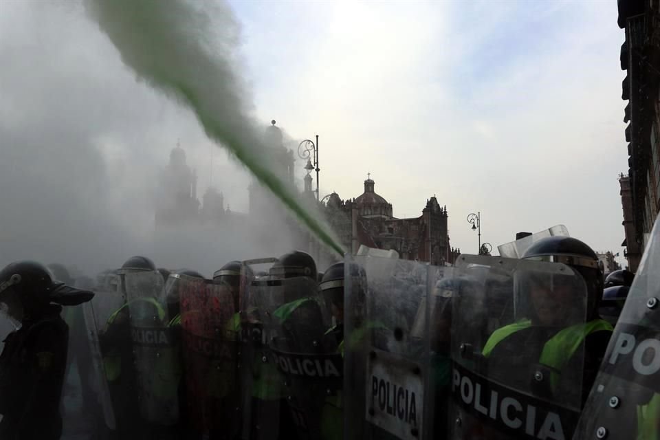 Mujeres policías activan extintores contra manifestantes que les lanzaban globos con pintura, vinagre, petardos y bombas molotov  frente al Palacio Nacional tras la marcha del #8M.