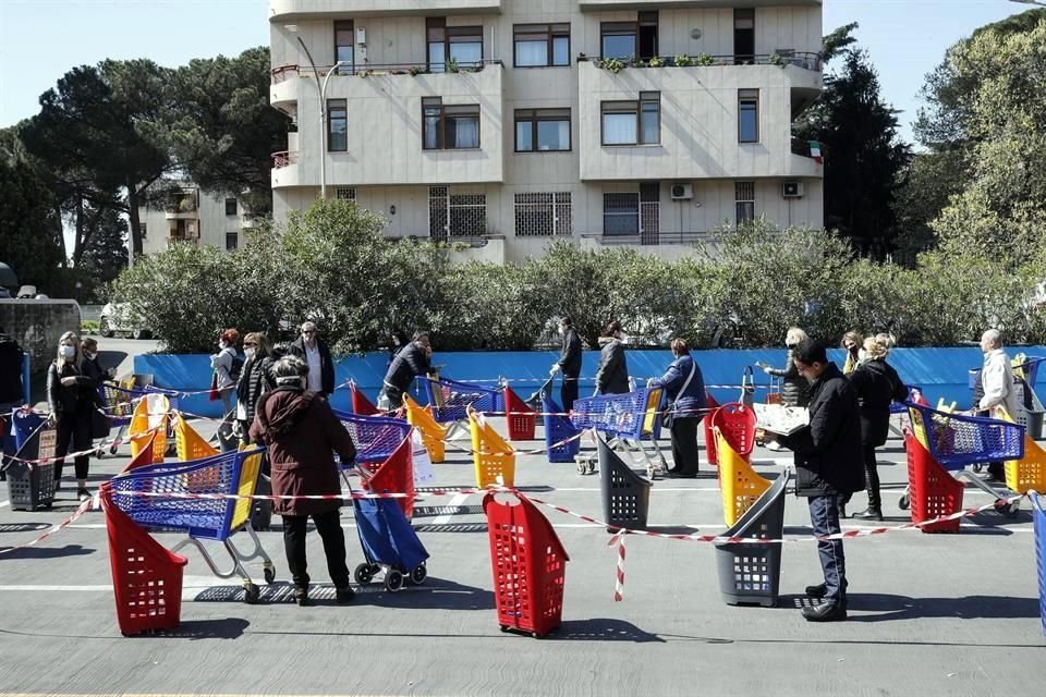 Personas esperan para hacer pagos en un supermercado de Roma guardando distancia.