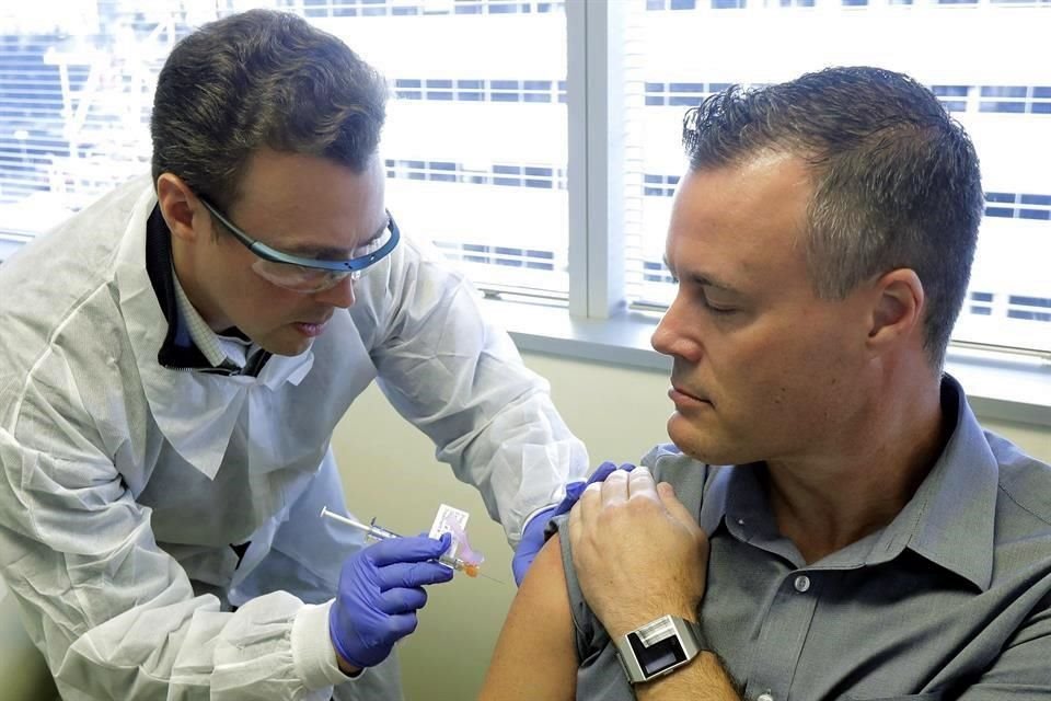 El farmacéutico Michael Witte le da una inyección a Neal Browning en el estudio de primera etapa de una posible vacuna contra el coronavirus