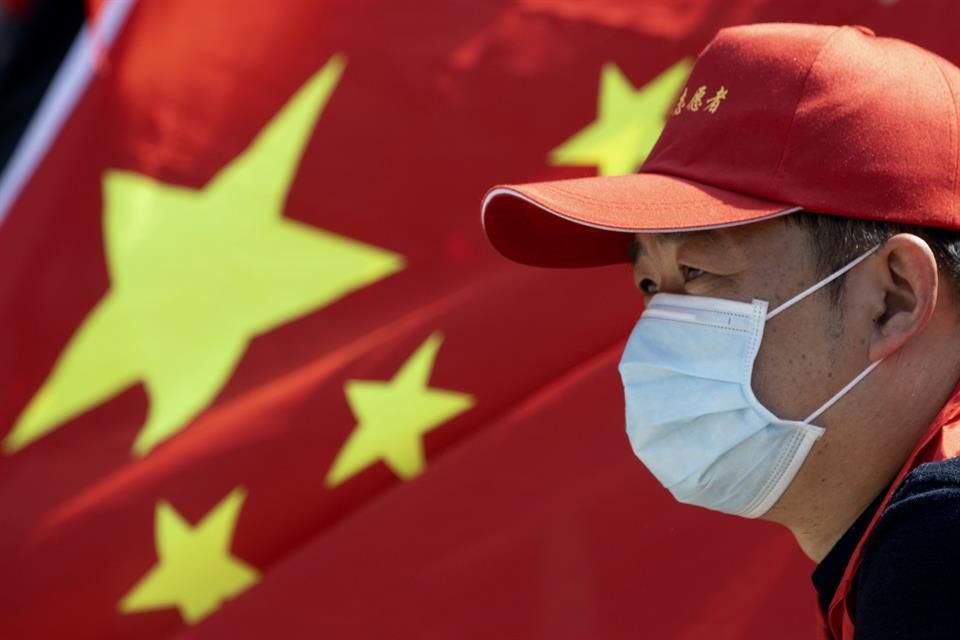 A volunteer looks out near a Chinese national flag during a farewell ceremony for the last group of medical workers who came from outside Wuhan to help the city during the coronavirus outbreak.