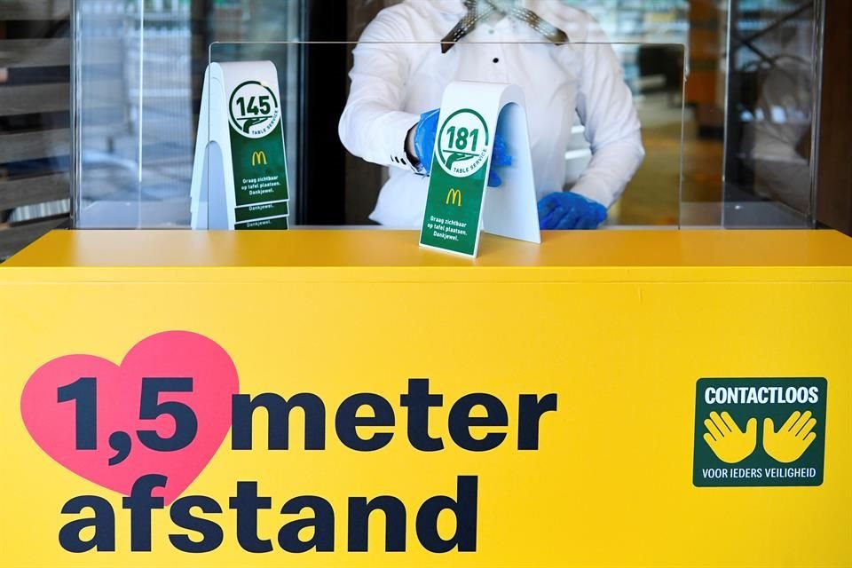 An employee handles table service numbers for clients inside a prototype location of fast food giant McDonald's for restaurants which respect the 1.5m social distancing measure.