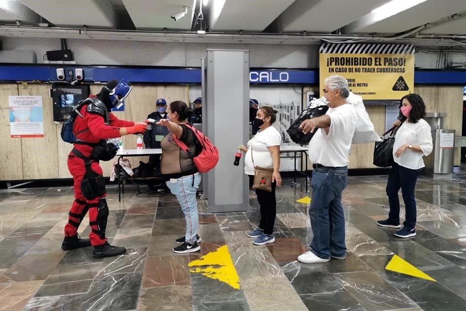 Al interior del Metro, personal con trajes especiales realiza revisiones a los usuarios.