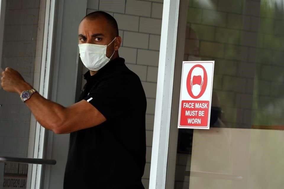 Un hombre con mascarilla sale de un restaurante en Miami.