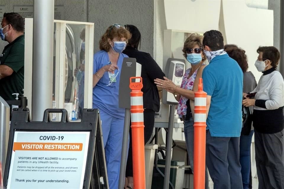 Varias personas hacen fila usando cubrebocas para entrar a un hospital en Miami.