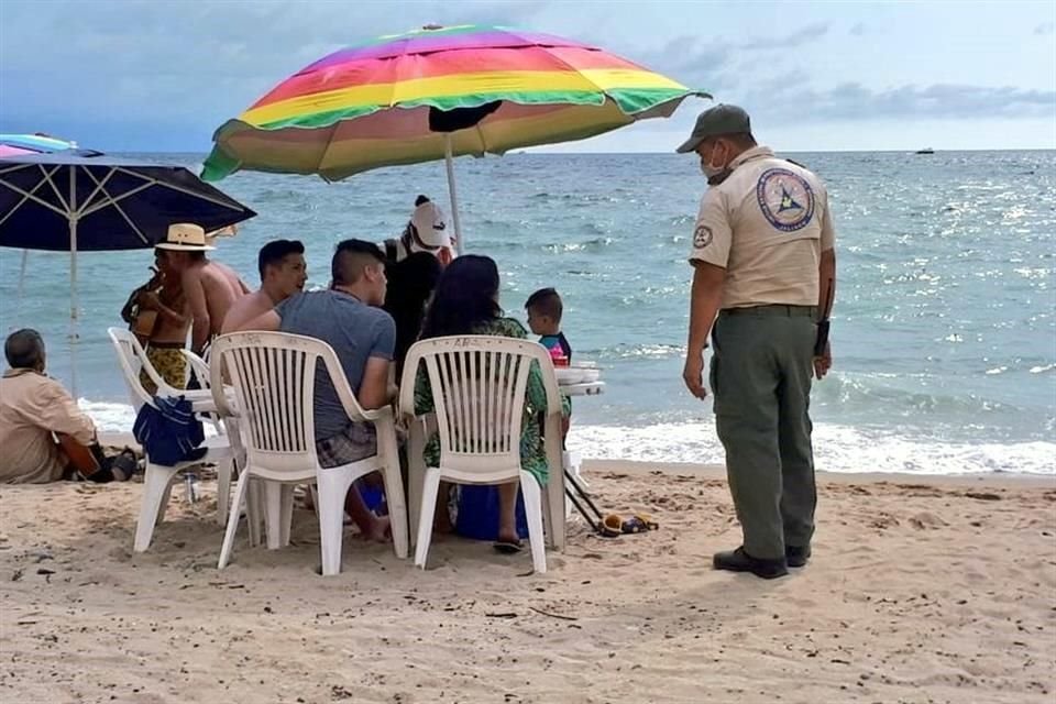 Personal de Protección Civil realiza recorridos en las playas de Puerto Vallarta para hacer recomendaciones de sanidad a los paseantes. No todos las acatan.