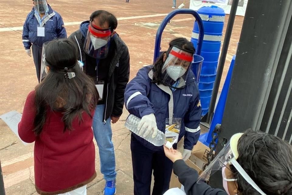 A su ingreso al estadio, a los aspirantes se les proporciona alcohol gel y se les toma la temperatura.