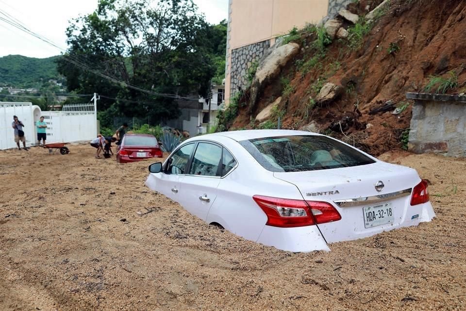 Dos autos atrapados en la tierra luego de fuertes lluvias.