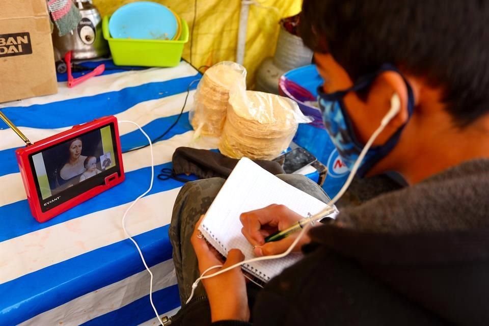 Debido a la pandemia, Jorge, un estudiante de tercer grado de Secundaria, toma clases en línea en el puesto de tacos de sus padres.