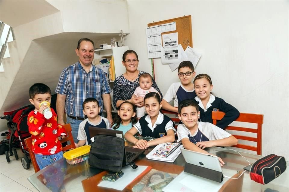 La familia posa en su casa durante un día de clases en linea.