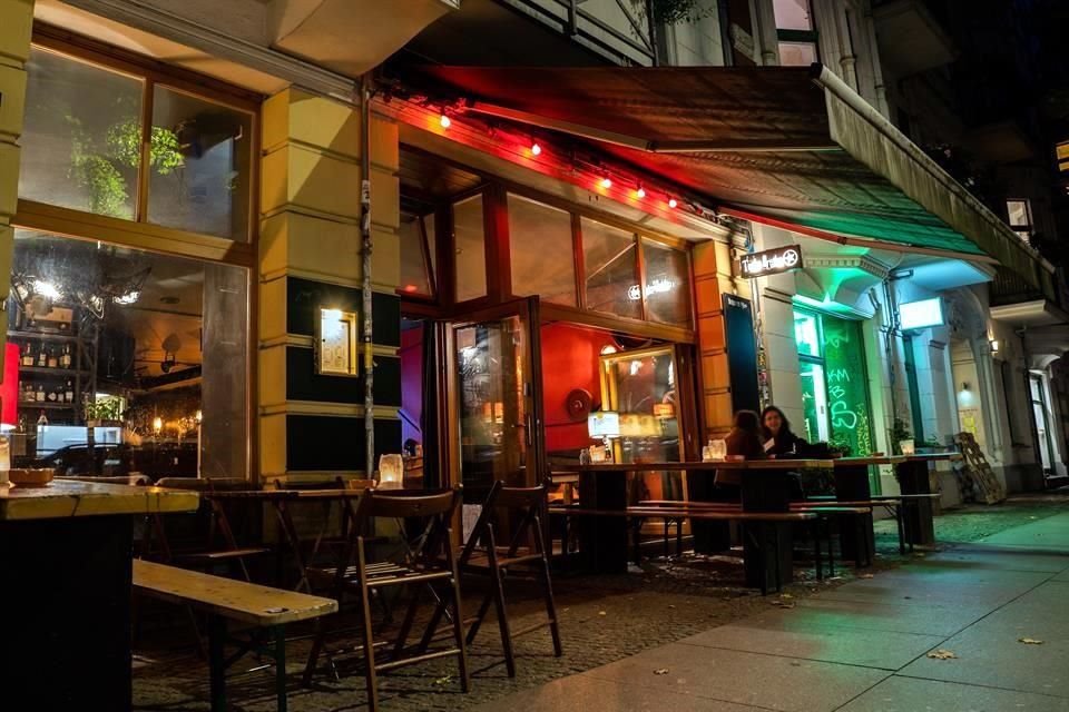 Dos personas charlan en mesas fuera de un bar en Berlín, Alemania.