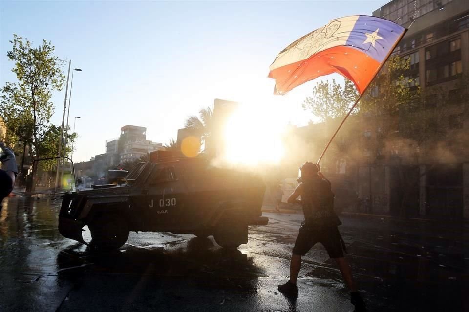 Un manifestante ondea una bandera chilena junto a un camión de Carabineros en Santiago, Chile.