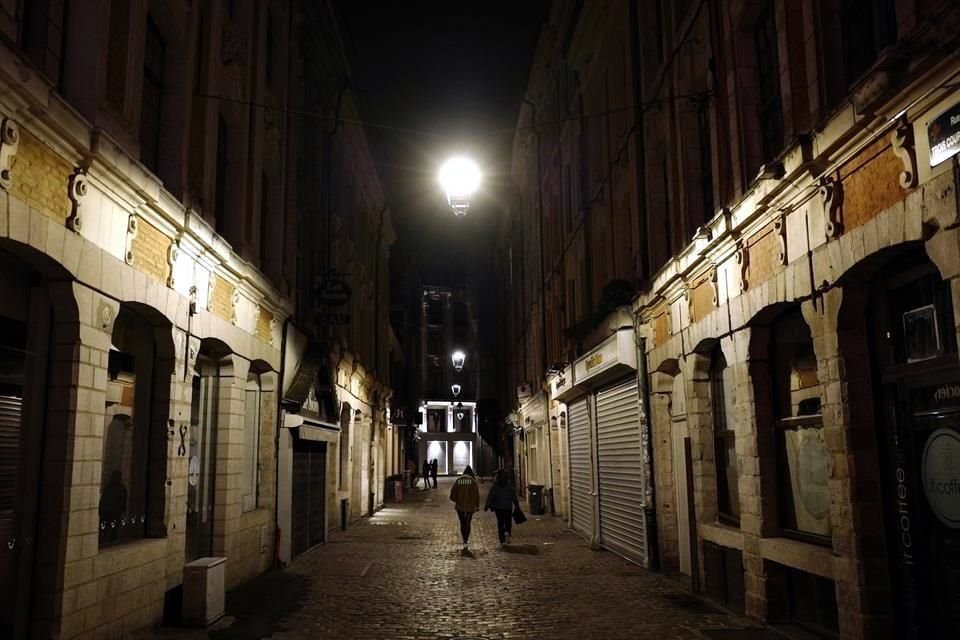 Personas en Lille, al norte de Francia, caminan por una calle vacía.