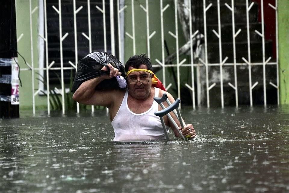Un hombre camina con algunas pertenencias entre el agua.