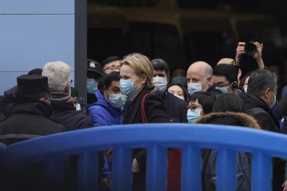 El equipo de la Organización Mundial de la Salud recibe instrucciones fuera del mercado de mariscos de Huanann en su tercer día de su visita de campo en Wuhan, China este domingo.