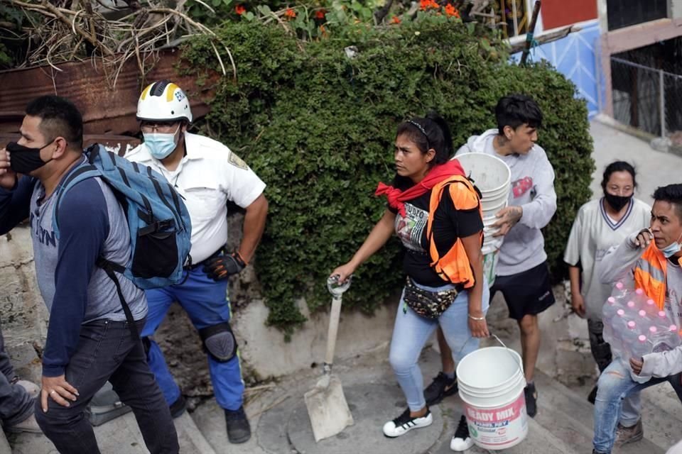 Una mujer sostiene una pala mientras espera para ingresar al sitio.