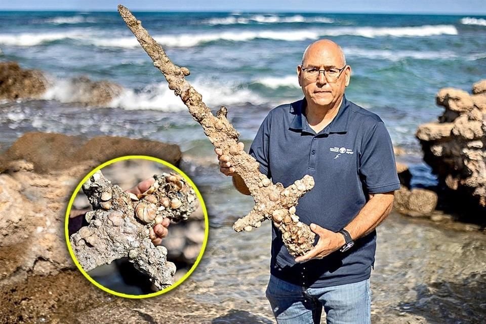 Kobi Sharvit, jefe de arqueología submarina de la AIA, sostiene la espada de un metro de largo, completamente cubierta de corales.
