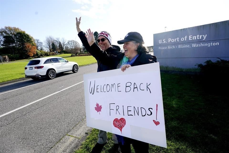 Traysi Spring y su esposo Tom Bakken sostienen un cartel de bienvenida en la frontera entre EU y Canadá.