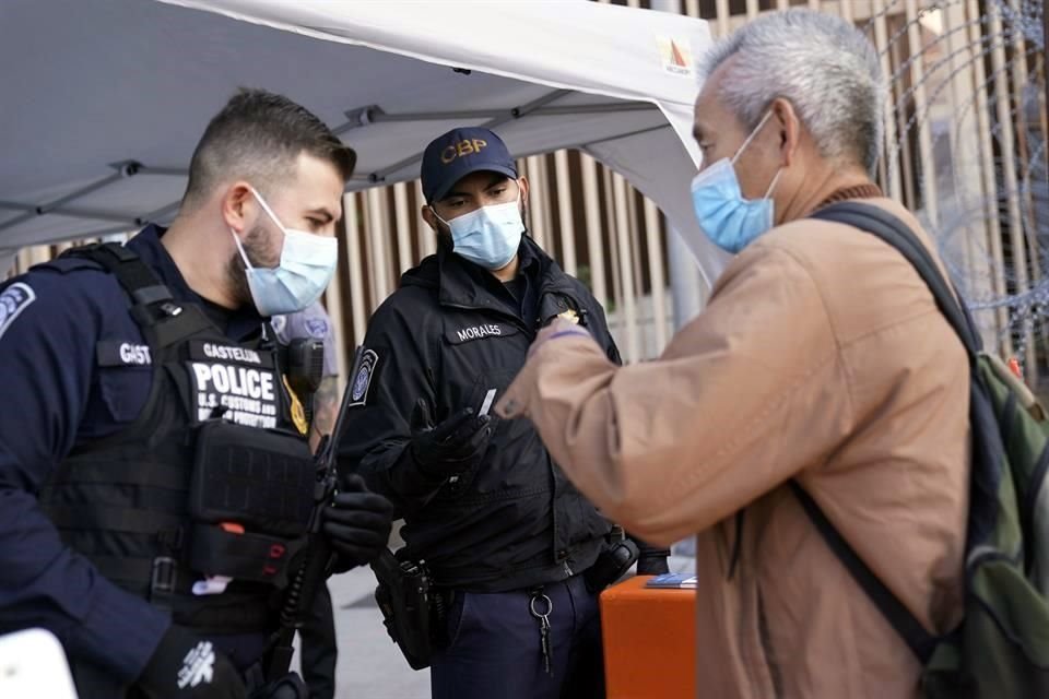 Oficiales de EU hablan con un hombre en el puerto de entra de San Ysidro, en Tijuana.