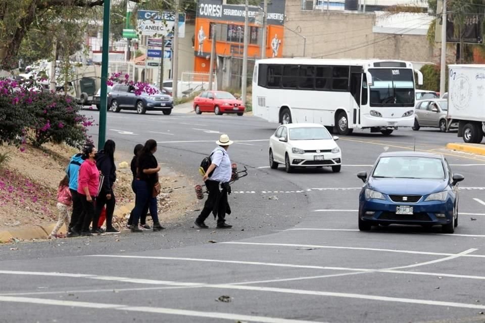 Familias completas se exponen para poder cruzar la avenida y llegar a la nueva parada del camión.