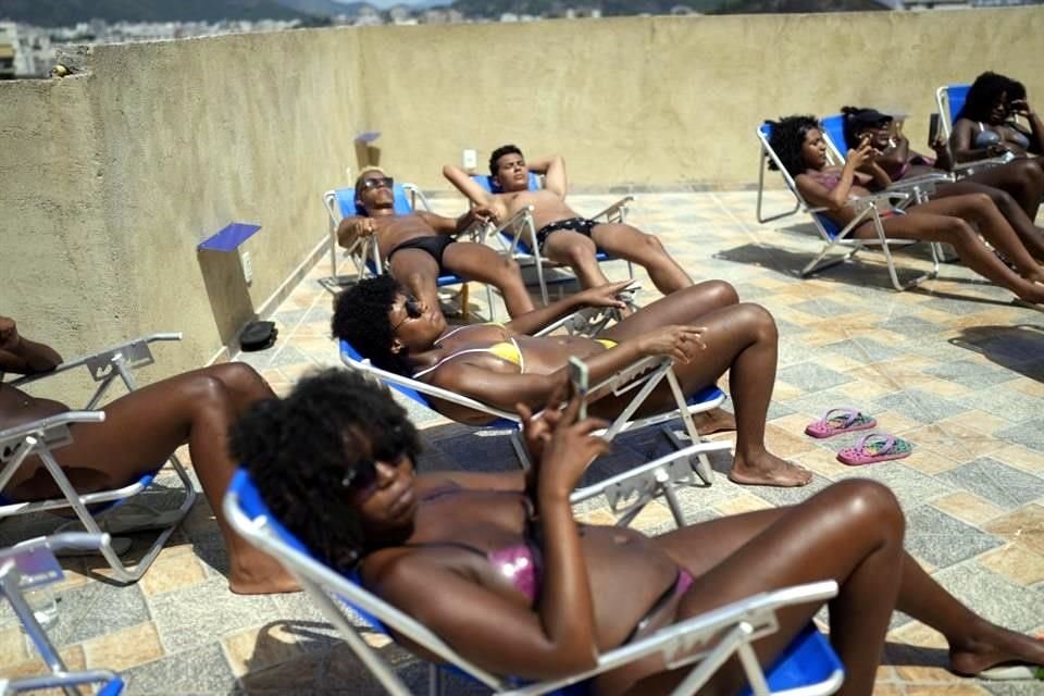 Personas toman en el sol en el salón de azotea 'Sabrina Bronze' en la favela Turano de Río de Janeiro, Brasil.