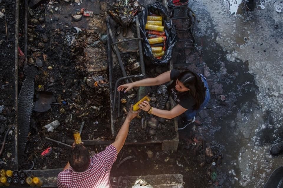 Locatarios del Mercado San Juan de Dios recogen las veladoras que no se dañaron, tras el incendio.