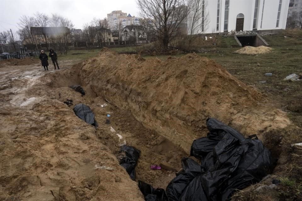 Los vecinos se reúnen junto a una fosa común en Bucha, en las afueras de Kiev, Ucrania.