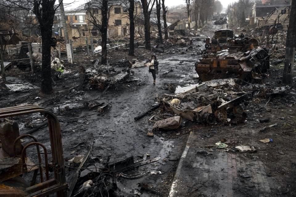 Una mujer camina por una avenida llena de tanques y vehículos destrozados en Bucha, a las afueras de Kiev.