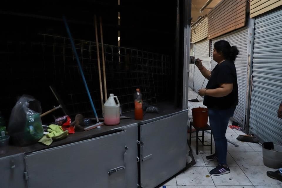 Una mujer pinta su local, dañado por el fuego que invadió al Mercado San Juan de Dios.