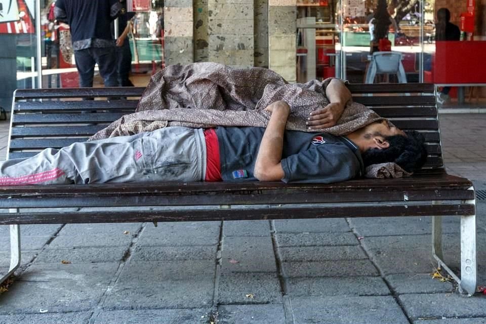 Un indigente duerme en la Plaza Tapatia, en el Centro de GDL.